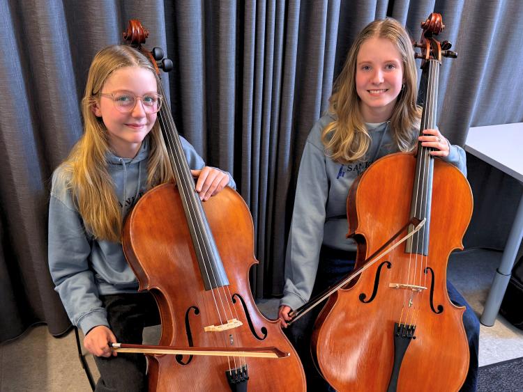 Et billede af Frieda og Christine, der sidder med hver deres cello